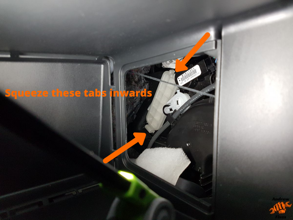 Picture showing the tabs to squeeze inwards to remove the cabin filter retaining cover on a Nissan Leaf